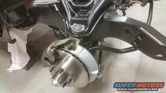 Front suspension assembly with disc brake rotor and caliper, black frame components, and a white cloth