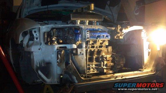 Car's engine bay with the engine out, showing the frame and some blue engine parts