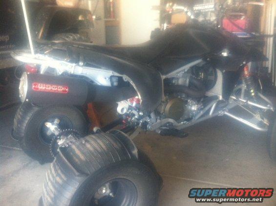 Quad bike with aftermarket exhaust and sand tires stacked in front