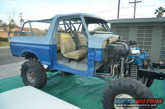 1979 Ford Bronco with roll cage, missing doors and hood, in blue and gray primer
