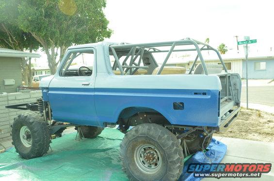 Blue and white 1979 Ford Bronco with roll cage, lifted on large tires