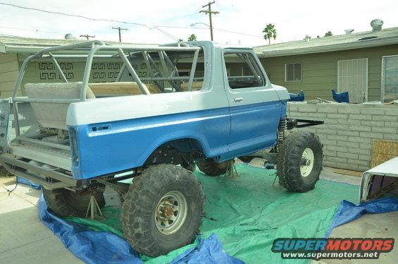 Modified 1978 Ford Bronco with roll cage, lifted suspension, and large tires, undergoing work