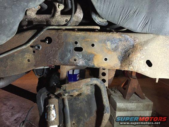Close-up of heavily rusted vehicle frame and suspension parts supported by jack stands