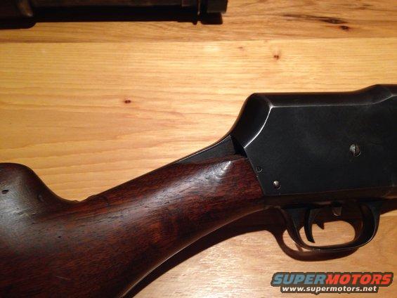 Close-up of a wooden shotgun stock and black metal receiver on a wooden surface