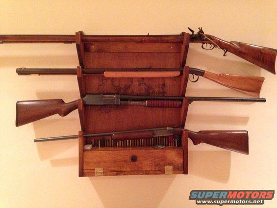 Wooden gun rack displaying several rifles and shotguns