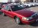 1995 Mercury Grand Marquis - Red sedan with a '03' sticker on windshield, parked in a lot with other cars.