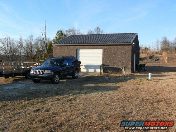 Dark blue Jeep Grand Cherokee parked in front of a garage
