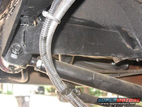 Underside view of vehicle frame with hoses and wiring. Supermotors.net logo visible