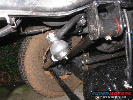 Undercarriage of a vehicle showing suspension components, tire, and differential. Text 'SUPERMOTORS' visible