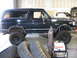 1988 Ford Bronco - A black Ford Bronco is shown in a garage setting, with spare tires and a welding machine visible.