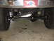 1988 Ford Bronco - Close-up view of the undercarriage, focusing on the steering and suspension system of a vehicle.