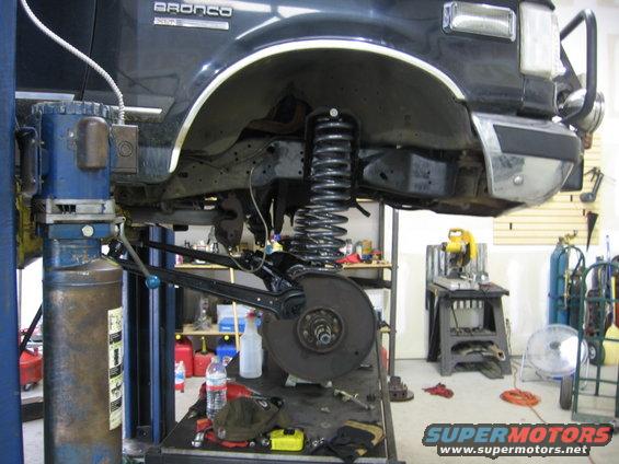 Front suspension of a 1988 Ford Bronco being worked on, lifted on a shop hoist