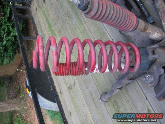 Red coil spring and suspension components on a wooden surface