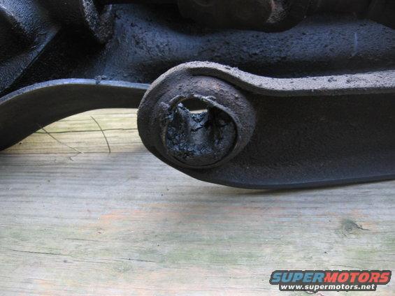Close-up of a heavily worn suspension bushing on a dark metal component