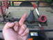 1988 Ford Bronco - Front axle assembly with red springs and shocks, with a hand obscuring part of the view.