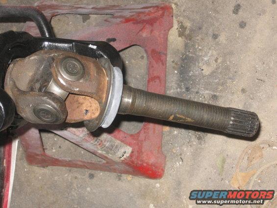 Driveshaft U-joint connected to a splined axle shaft, resting on red jack stands
