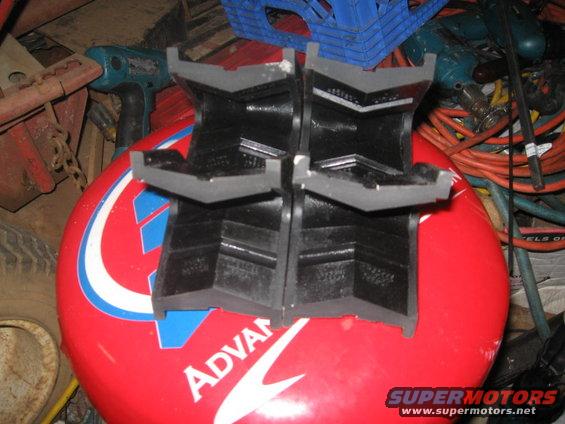 Four black rubber jack stands on a red surface with blue and white graphics, possibly a tire
