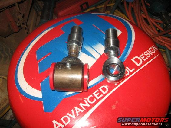 Two metal suspension components with red bushings on a red and blue circular surface with text
