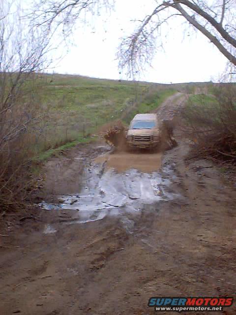 Van splashing through a mud puddle on a dirt road
