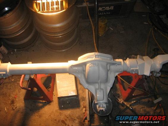 Differential axle assembly painted gray, supported by red jack stands in a workshop
