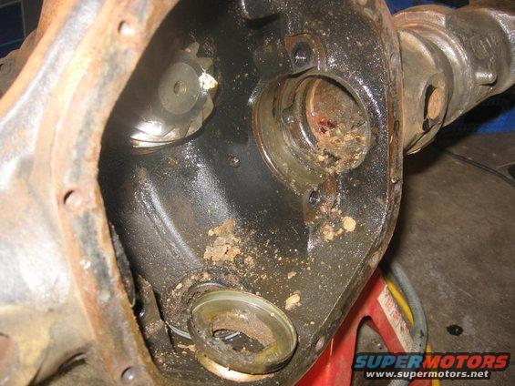 Differential housing with internal gears and bearing races, covered in dirt and rust