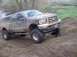 1976 Ford F-100 - This lifted Ford Super Duty pickup truck is covered in mud after driving on a dirt track.