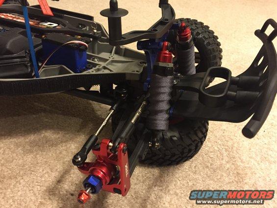 RC car suspension and chassis components. Red and blue anodized aluminum parts are visible
