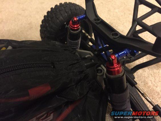 Red and blue shocks on a black remote control car chassis with a large tire