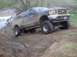 1976 Ford F-100 - This lifted SUV navigates a muddy off-road course, demonstrating its capabilities.