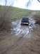 1976 Ford F-100 - A black pickup truck navigates a challenging muddy path with standing water.