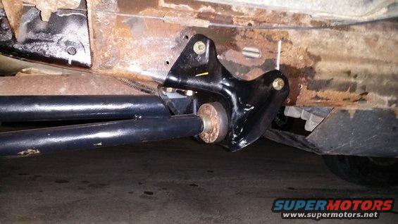 Undercarriage of a vehicle with rusty frame and black suspension components. A SuperMotors logo is visible