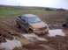 1976 Ford F-100 - A pickup truck struggles through a muddy off-road course with other vehicles visible in the background.