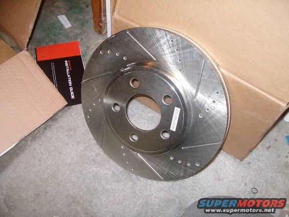 Perforated brake rotor with installation guide box in background