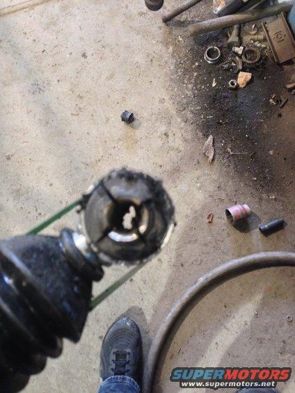 Damaged CV joint boot and axle part on concrete floor with tools scattered around