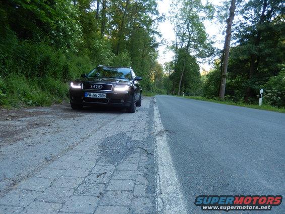 Dark sedan with license plate PB-WG 2006 parked on a paved shoulder