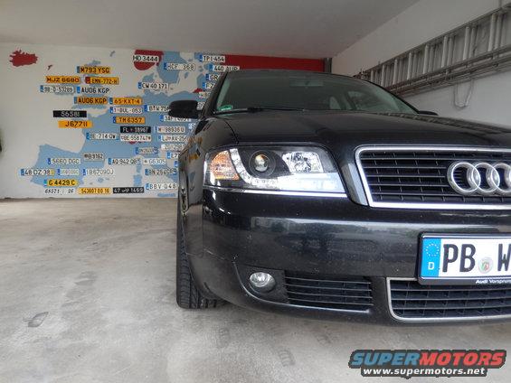 Front view of a black 2003 Audi A6 with a license plate and a map of Europe with license plates on the wall behind it