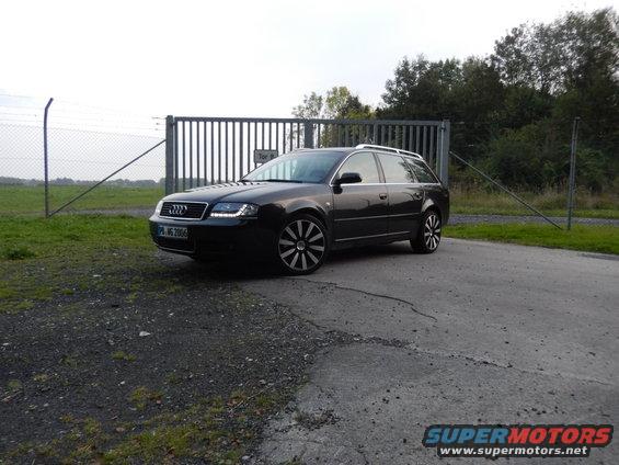 Dark station wagon with custom wheels parked near a gate. License plate reads 'PB-MS 2006'