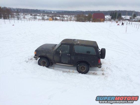Black SUV with spare tire on rear stuck in snow, side view