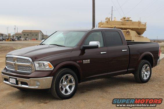 Brown Dodge Ram 1500 pickup truck parked outdoors, with a large yellow structure in the background
