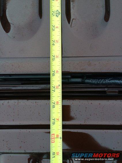 Yellow measuring tape showing inches from 72 to 81 against a dark, textured surface