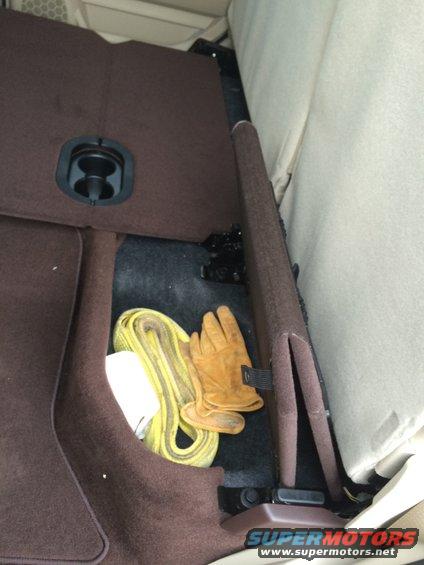 Interior storage compartment with a coiled yellow tow strap and brown work gloves