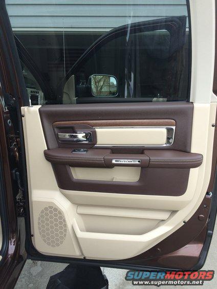 Interior of a truck door with brown and tan trim, chrome handle, and a speaker grille. The word 'RAM' is visible on the door panel