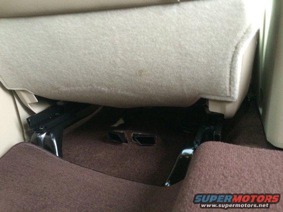 Under seat view of vehicle interior with visible seat rails and carpet