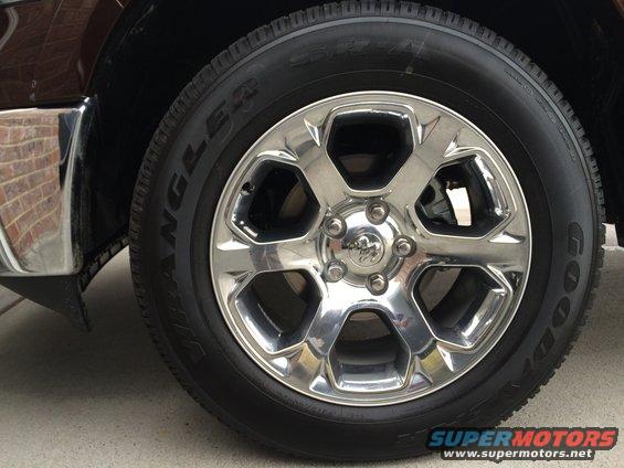 Chrome wheel with Ram logo on dark brown 2015 Dodge 1500 tire