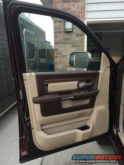 Interior of a truck door with brown and tan trim, showing the door panel, window controls, and side mirror