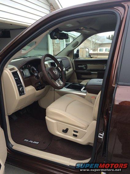 Brown pickup truck interior with tan leather seats, dashboard, steering wheel, and floor mats with "RAM" logo