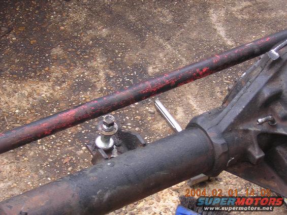 Close-up of a vehicle's rear axle assembly with a red-painted bar above it