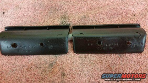 two black plastic automotive parts with numbers stamped on them