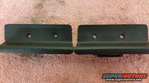 Two black plastic trim pieces with two screw holes each, lying on a pink textured surface. A Supermotors logo is in the lower right