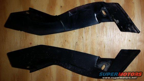 Two black plastic automotive trim pieces on a wooden surface